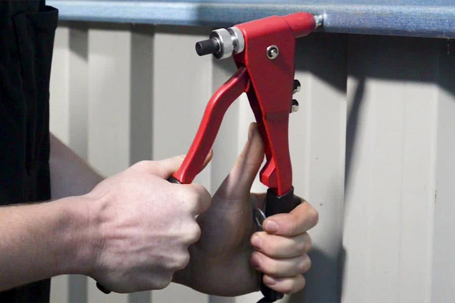 انبر پرچ در حال اتصال دو قطعه فلزی با میخ پرچ