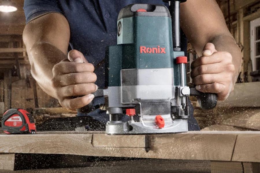 اور فرز نجاری در حال برش و فرم‌دهی لبه چوب در کارگاه نجاری